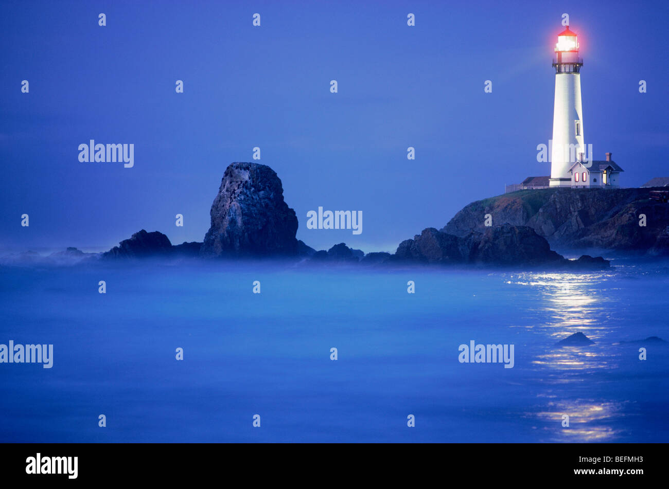 Pigeon Point Lighthouse beam reflecting across Pacific Ocean waters and rocky shore at Pescadero California USA Stock Photo