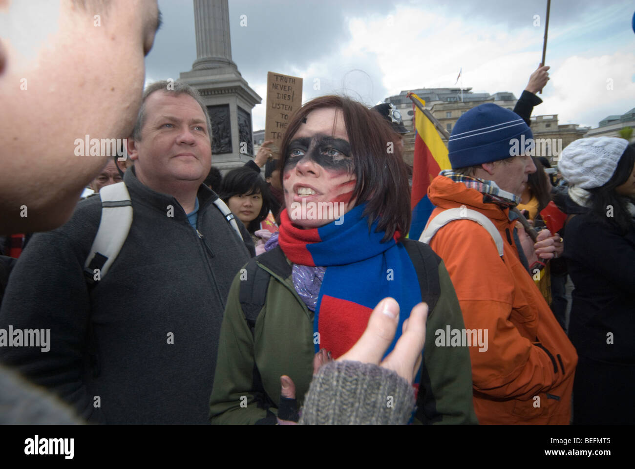 woman with Free Tibet  scarf and face paint listens in argument in Trafalgar Sq as Beijing Olympic relay passes through London Stock Photo