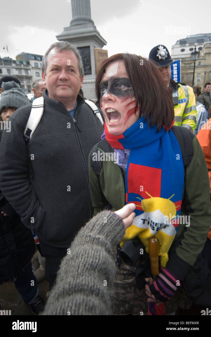 Police watch angry woman pro-Tibet demonstrator in argument in Trafalgar Sq as Beijing Olympic relay passes through London Stock Photo