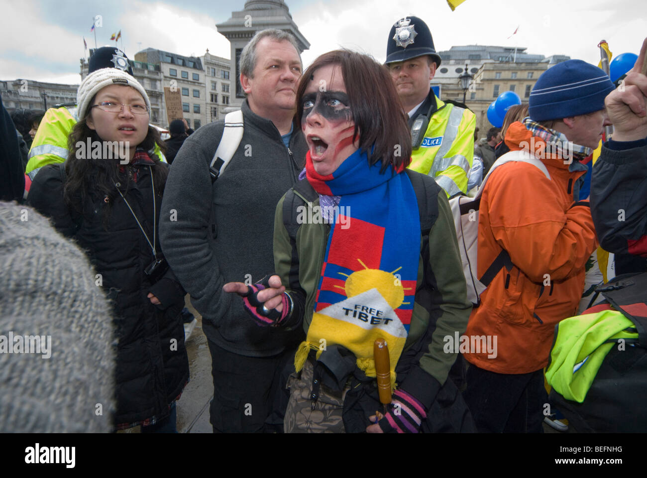 Police watch angry woman pro-Tibet demonstrator in argument in Trafalgar Sq as Beijing Olympic relay passes through London Stock Photo