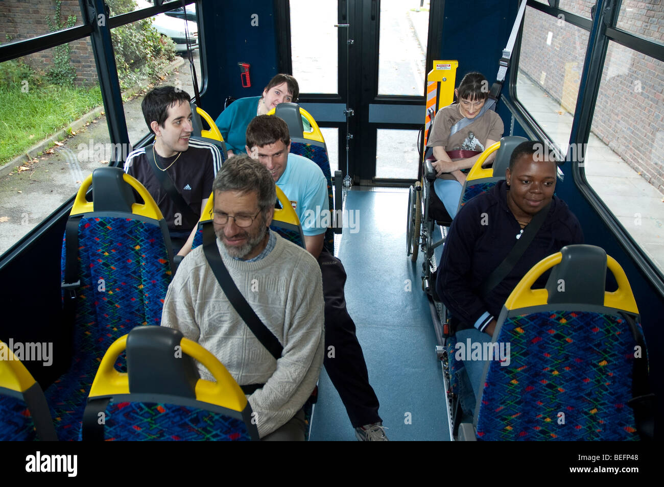 Loading a disabled person in a wheelchair into the rear entrance of a special purpose mini bus Stock Photo