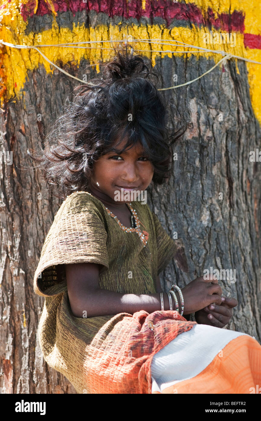 Young Indian street girl, sitting in front of a tree, smiling Stock Photo