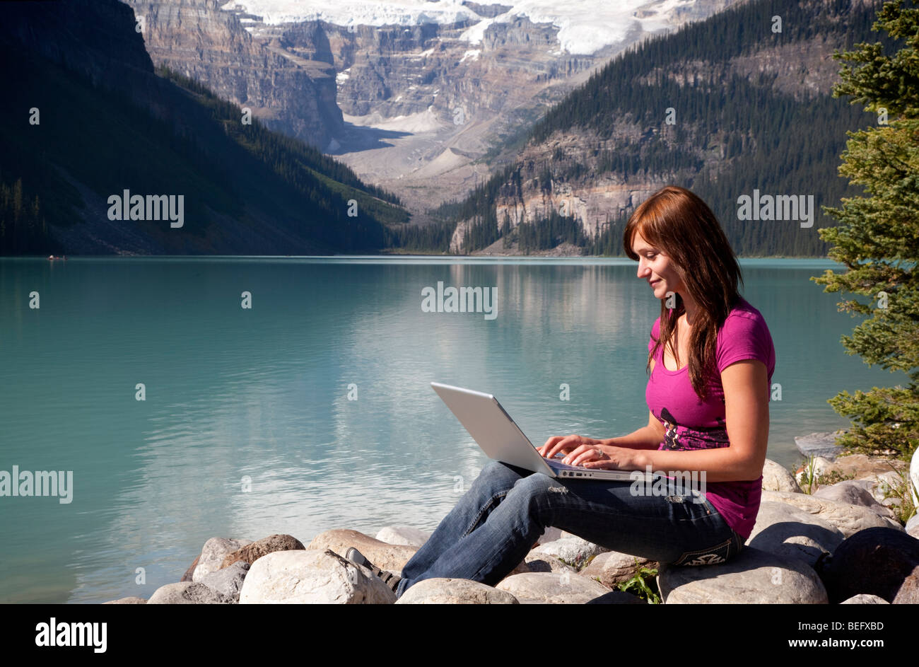 Young woman using a laptop by the lake Stock Photo