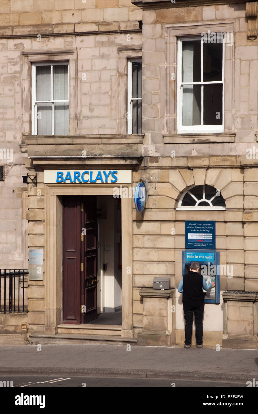 Alnwick, Northumberland, England, UK. Barclays Bank with person using Hole in the Wall ATM Stock Photo
