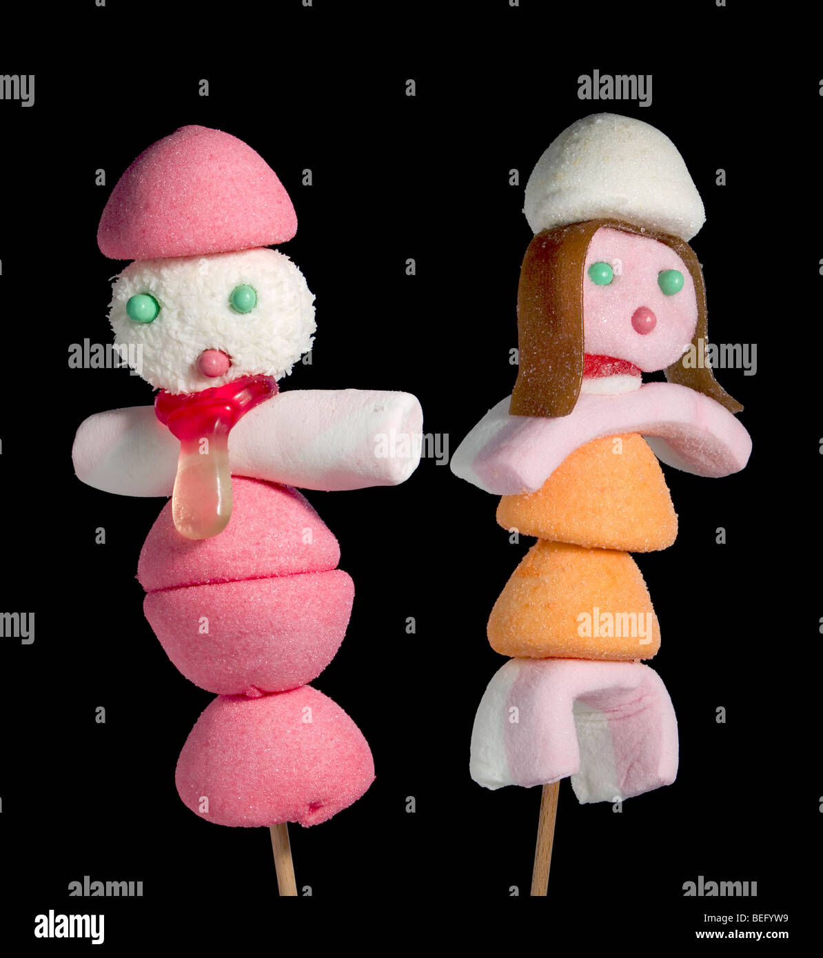 A male and a female figurine made out of candies on a stick over a