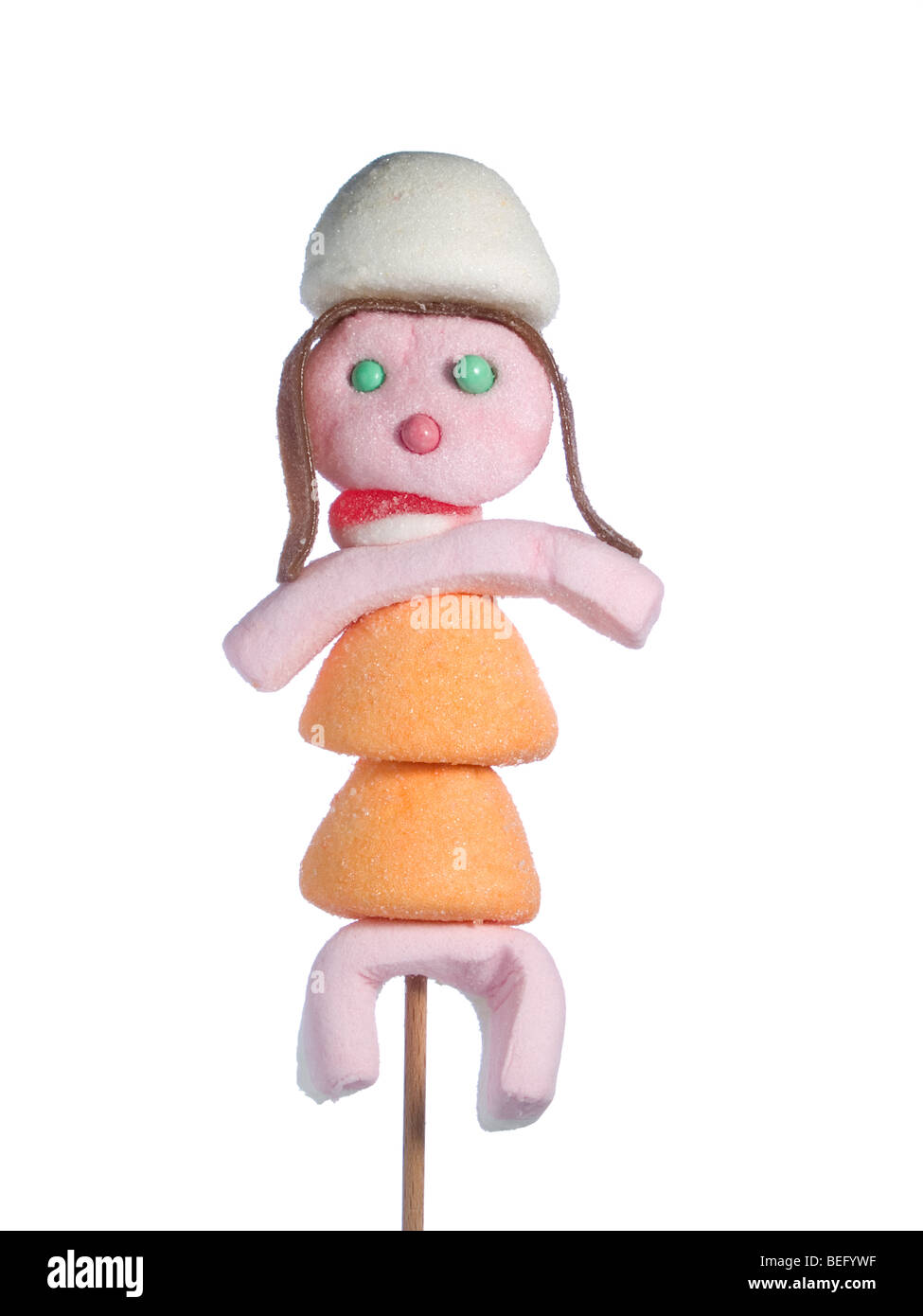 A female figurine made out of candies on a stick over a white