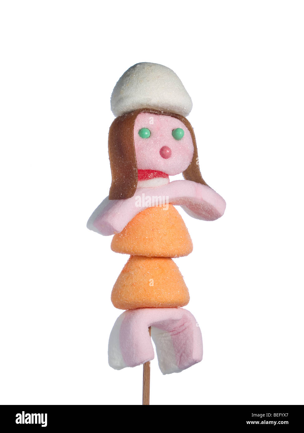 A female figurine made out of candies on a stick over a white