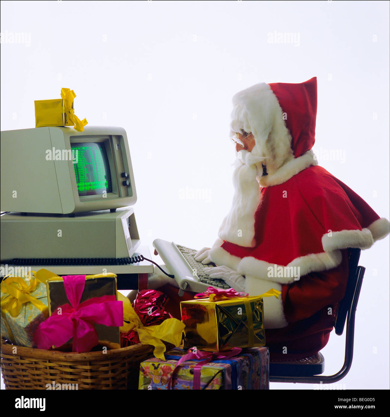 Santa Claus typing on a 1980s IBM personal computer, Christmas presents Stock Photo