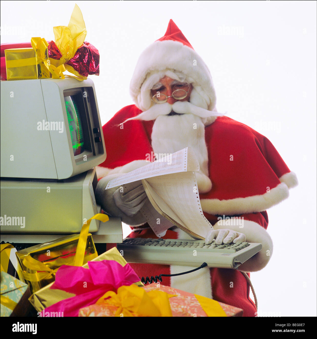 Santa Claus checking presents list with a 1980s IBM personal computer Stock Photo