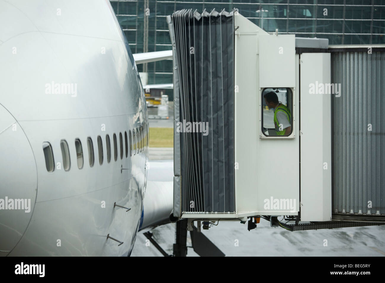 British Airways jetty operator carefully manoeuvres towards arrived BA aircraft door at Heathrow's Terminal 5. Stock Photo