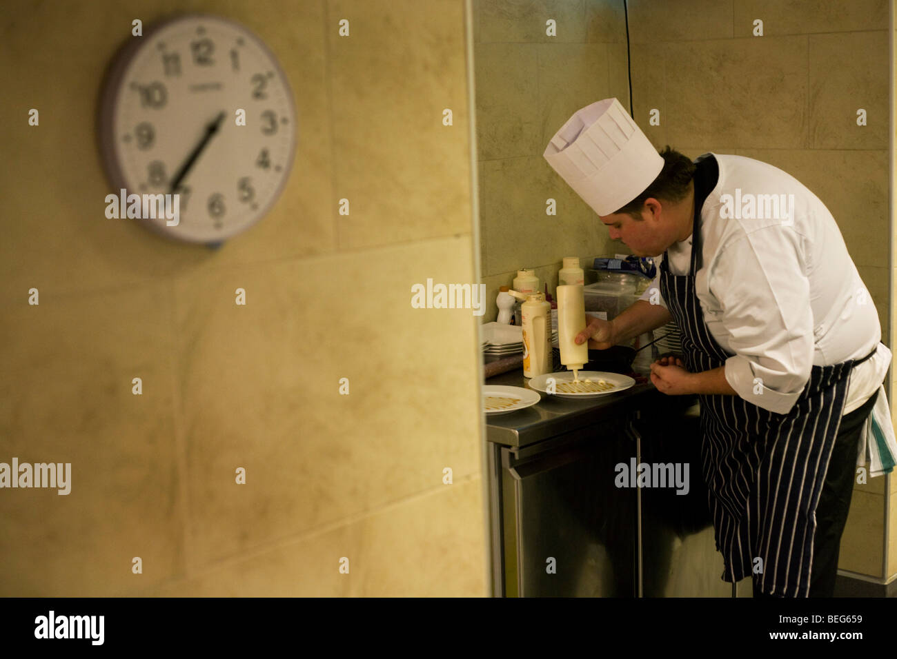 A chef puts finishing touches on deserts in the kitchens at the Vivre restaurant in Sofitel. Stock Photo