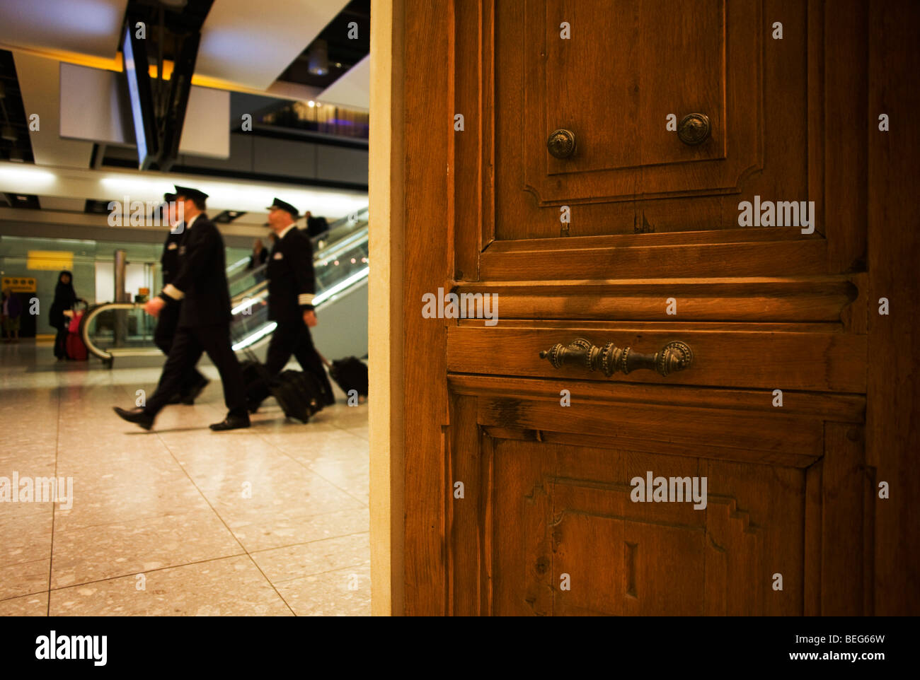 Passing air crew walk past the Paul Smith château door at Heathrow airport's terminal 5 Stock Photo