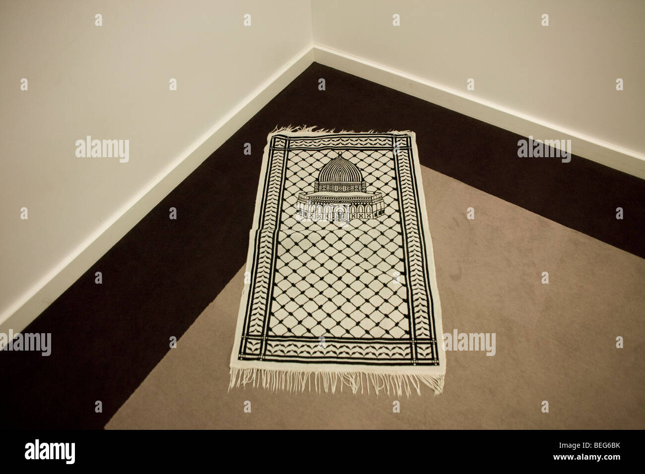 An Islamic prayer mat positioned towards Eastern Mecca in a corner of the Multi-faith room at Heathrow T5. Stock Photo