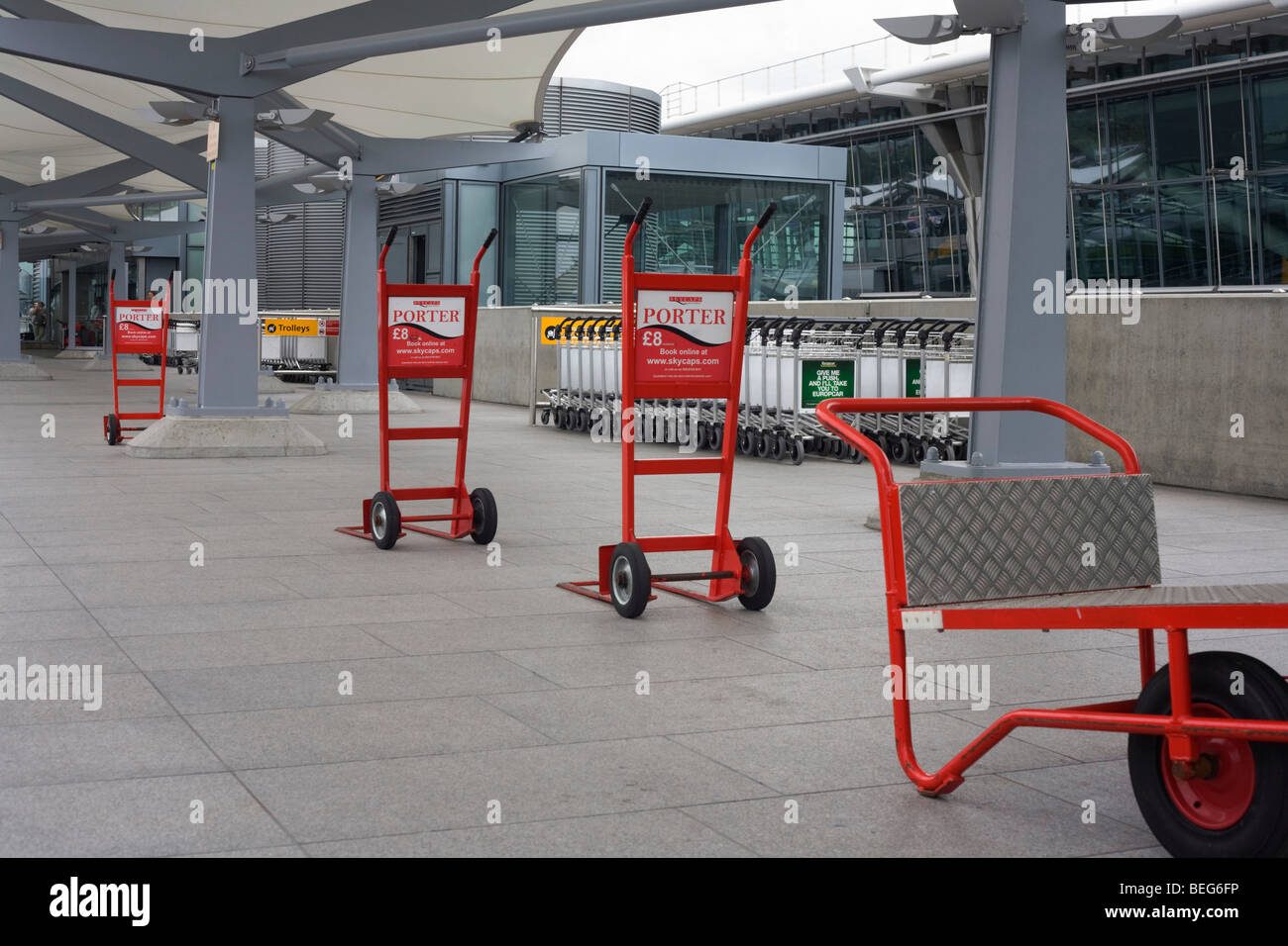 Skycap baggage trolleys line up awaiting business on the upper level in Departures at Heathrow airport's Terminal 5. Stock Photo