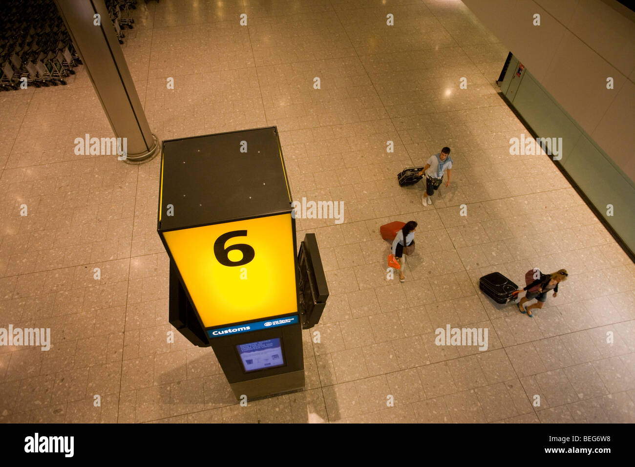 Aerial view of passengers towing wheelie baggage in the baggage reclaim hall in the arrivals of Heathrow Airport's T5 Stock Photo