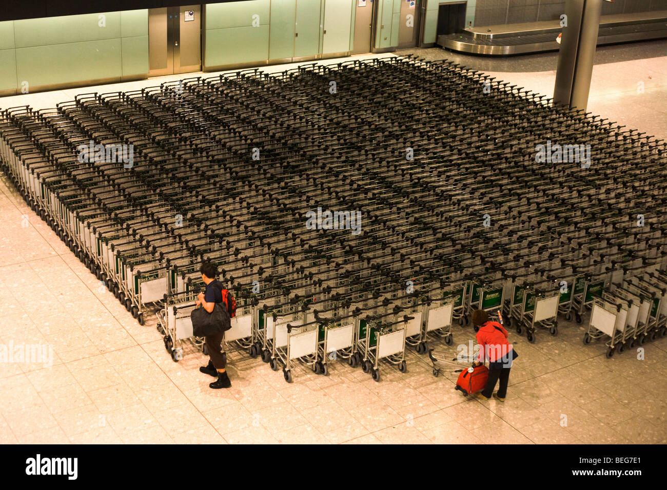 Airline passengers collect trolleys in the baggage reclaim hall in the