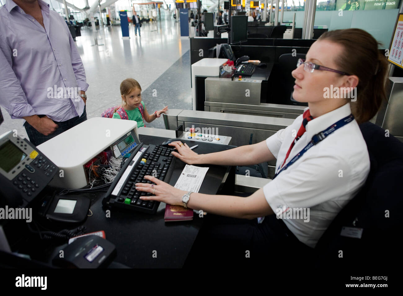 Young girl and her father check-in for a British Airways flight at Heathrow Airport's Terminal 5. Stock Photo