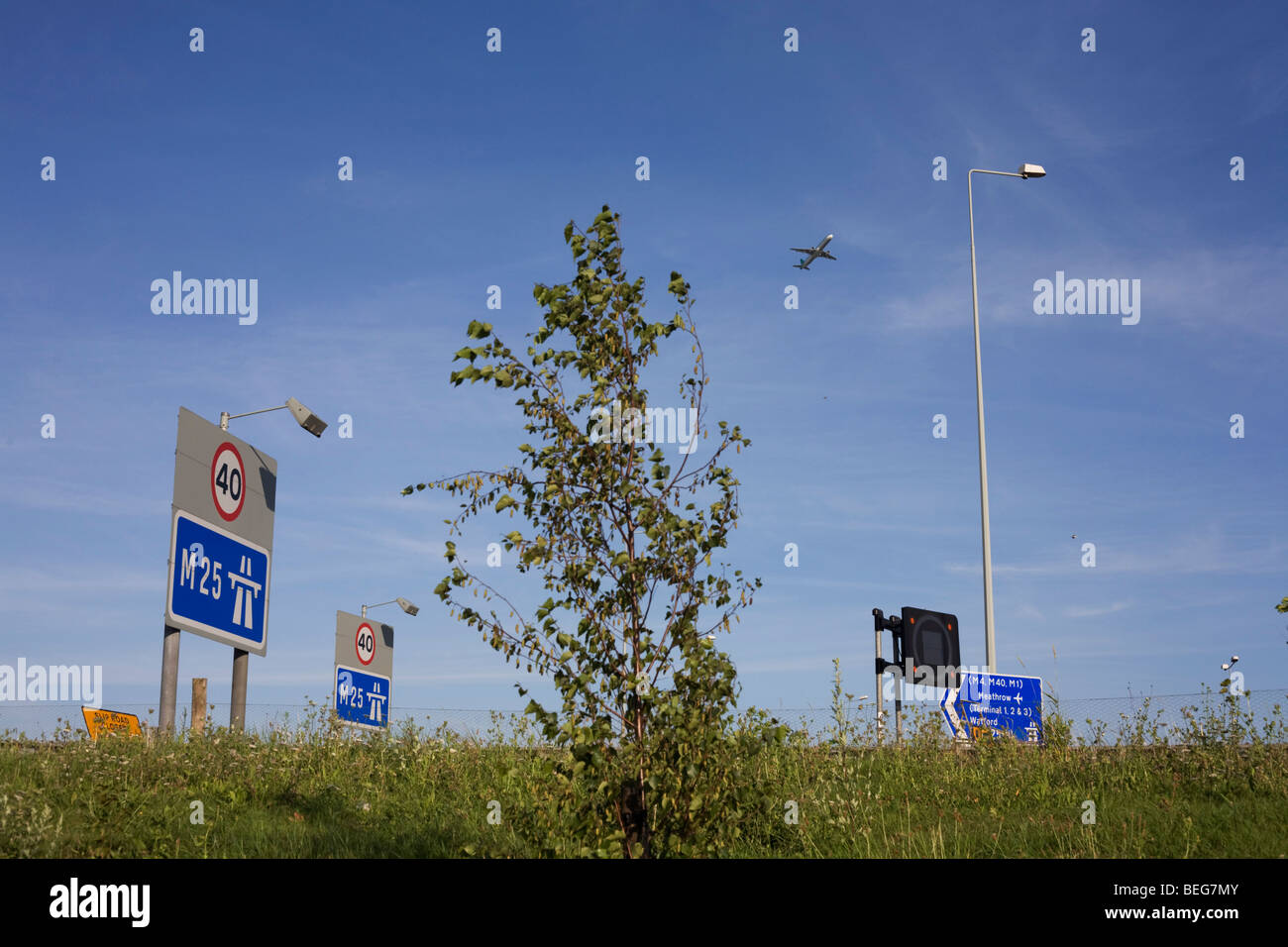 A passing airliner that passes overhead on a flight-path from Heathrow airport over M25 at Poyle on Colne Valley Way. Stock Photo