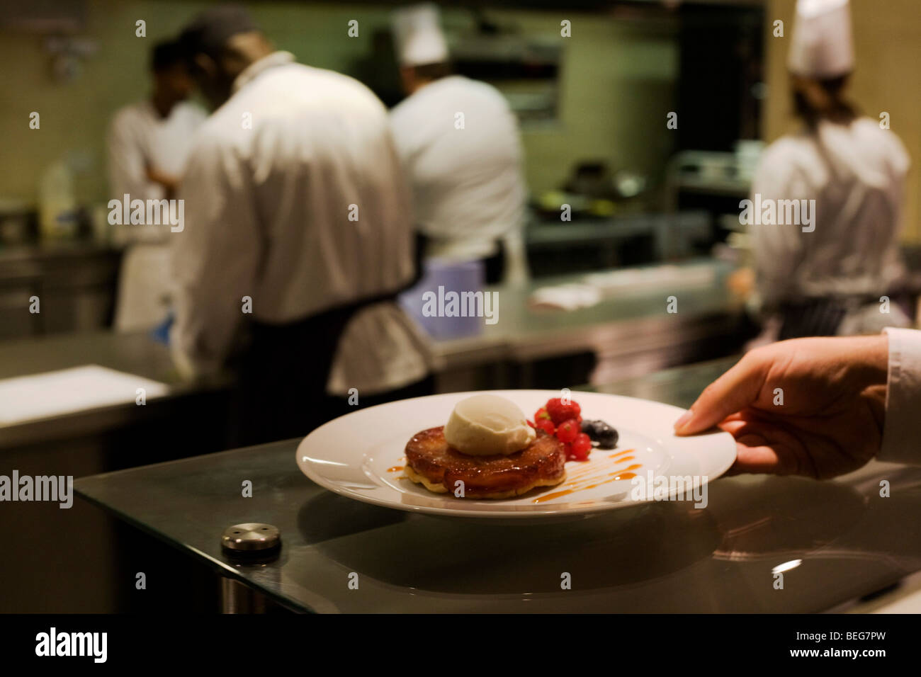 A waiter reaches for a finished Tarte Tatin desert dish at the Vivre restaurant in Sofitel. Stock Photo