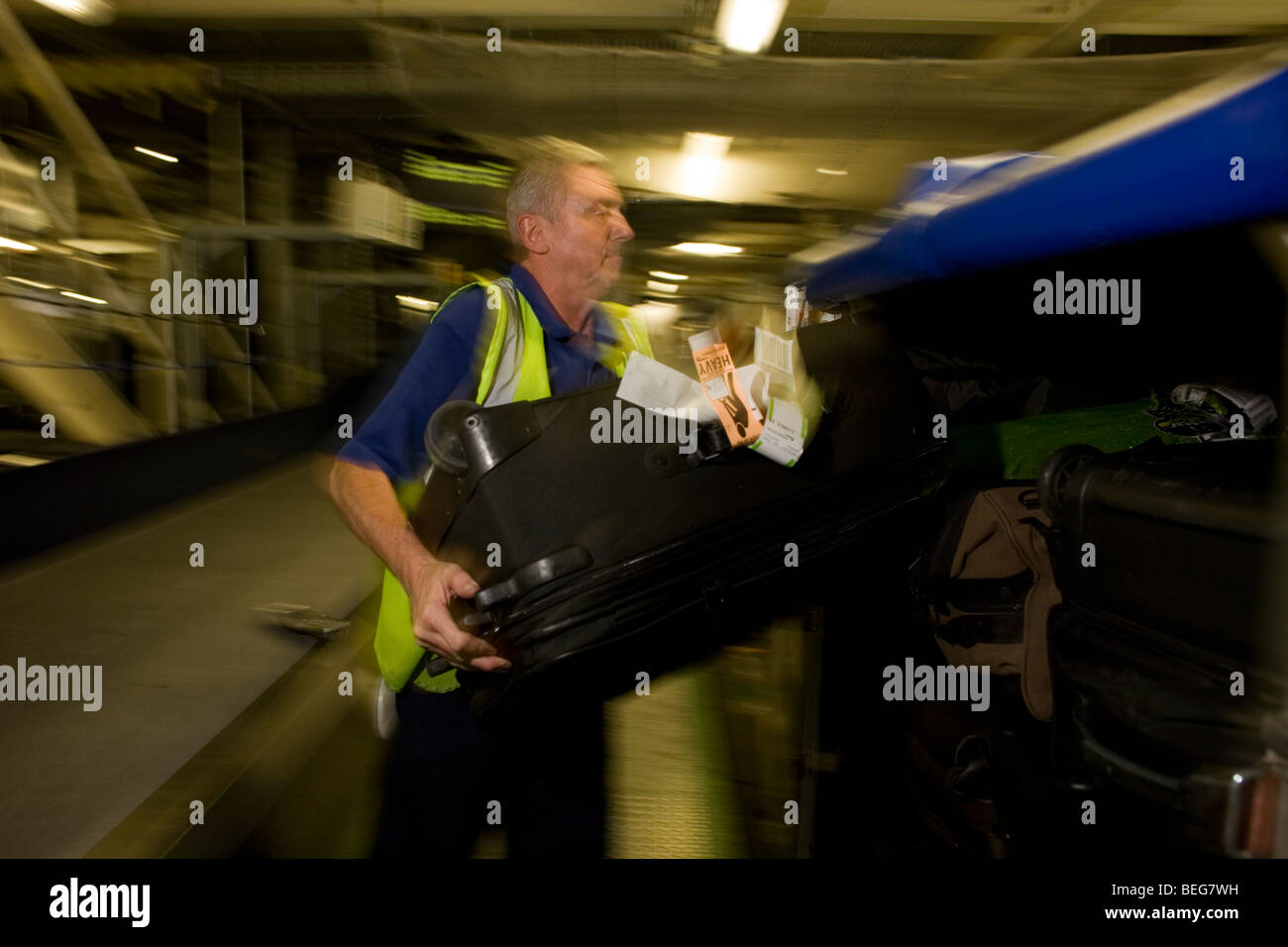 A British Airways baggage loads passengers' possessions into an airline container at Heathrow terminal 5. Stock Photo