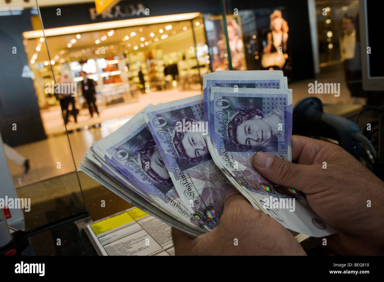An assistant counts through Pounds Sterling notes at the Travelex bureau de change at Heathrow Airport's Terminal 5. Stock Photo