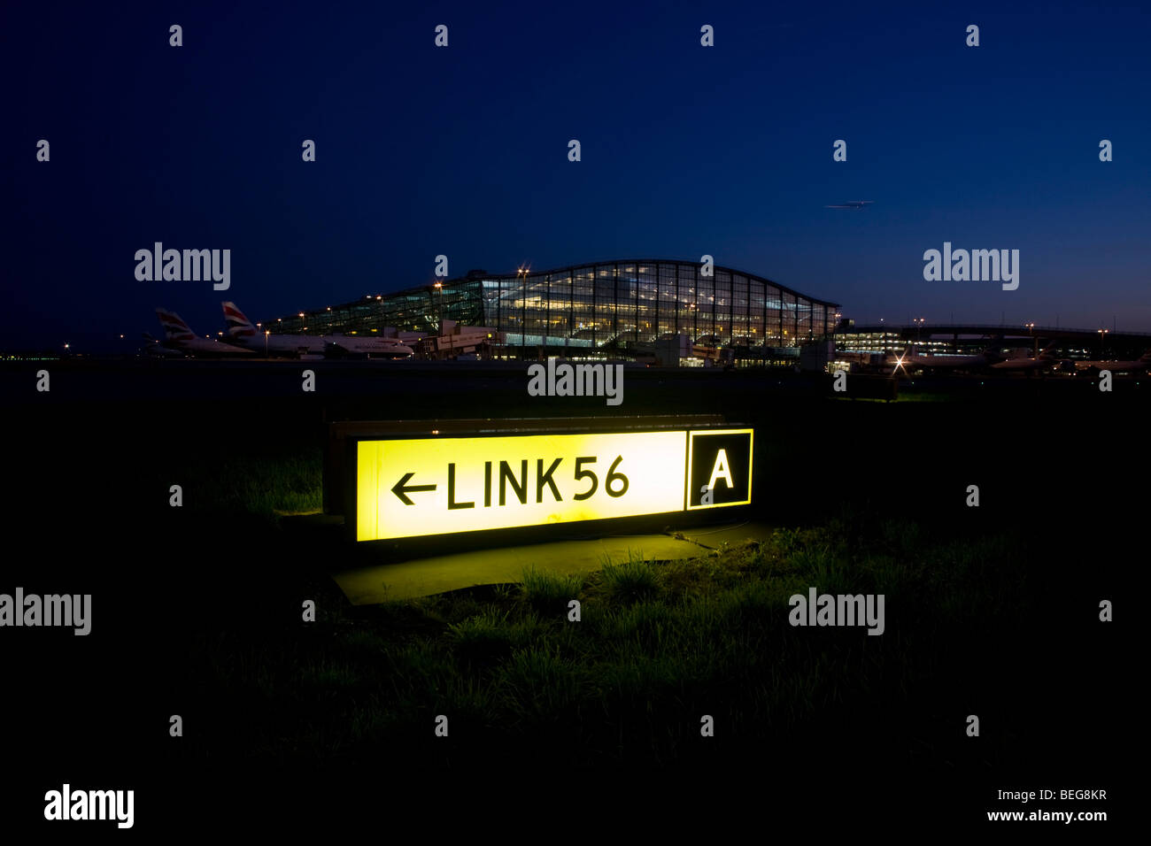 An exterior dusk view Terminal 5 building and a taxiway sign for pilots to navigate around a complicated Heathrow airfield Stock Photo