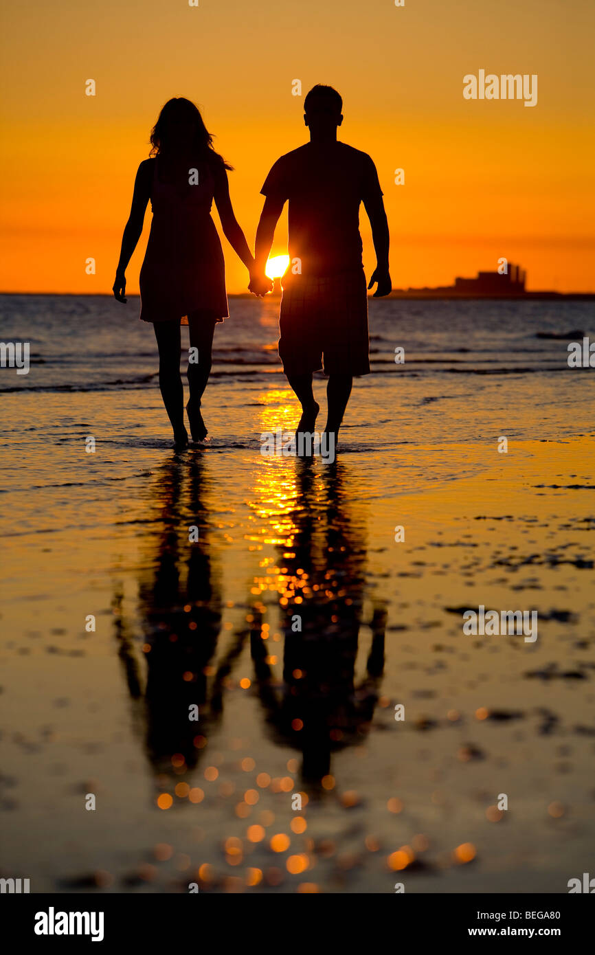 A couple walking the beach at sunset. Stock Photo