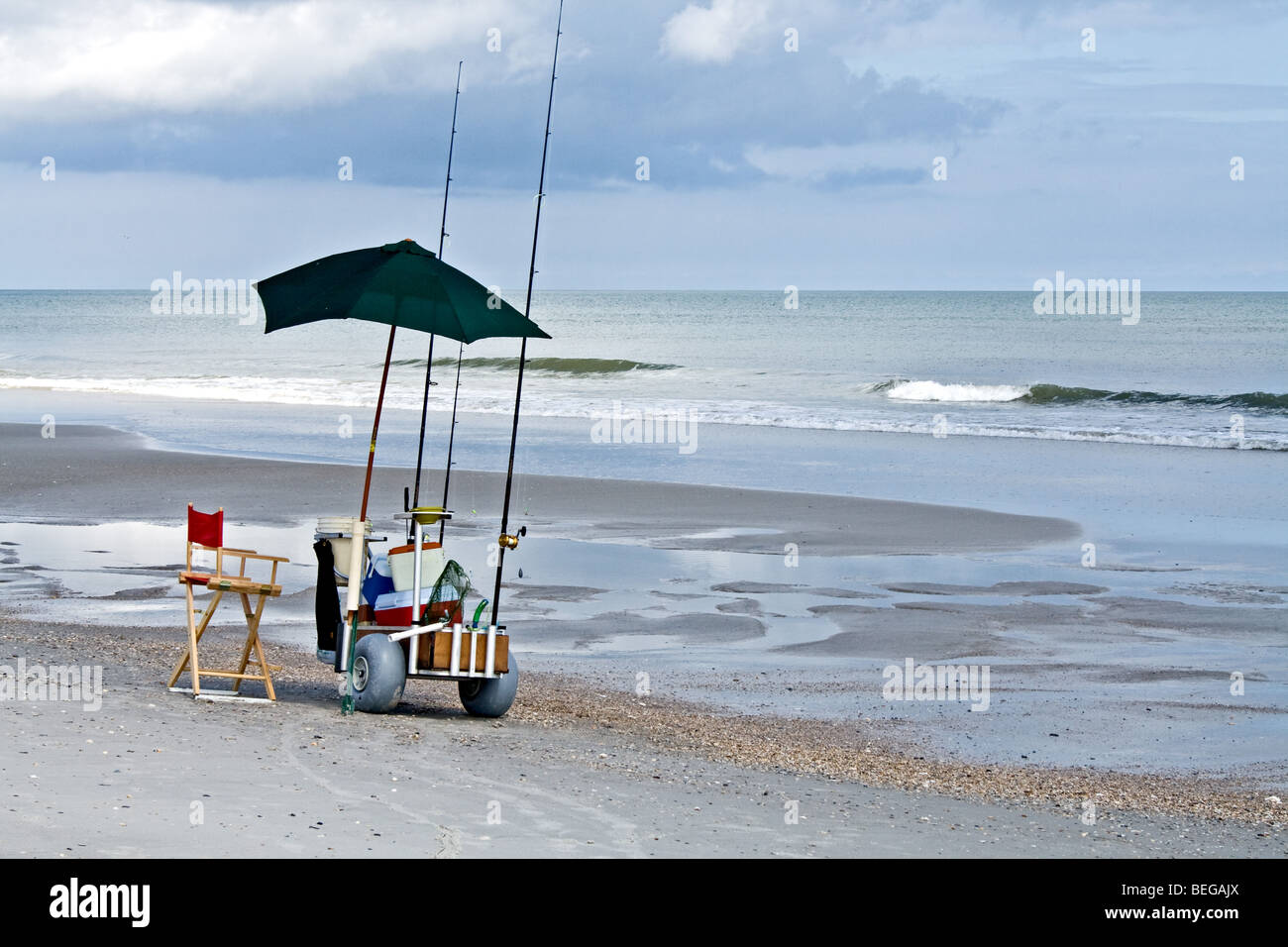 Fishing gear, umbrella and cooler on a wheeled cart on the beach