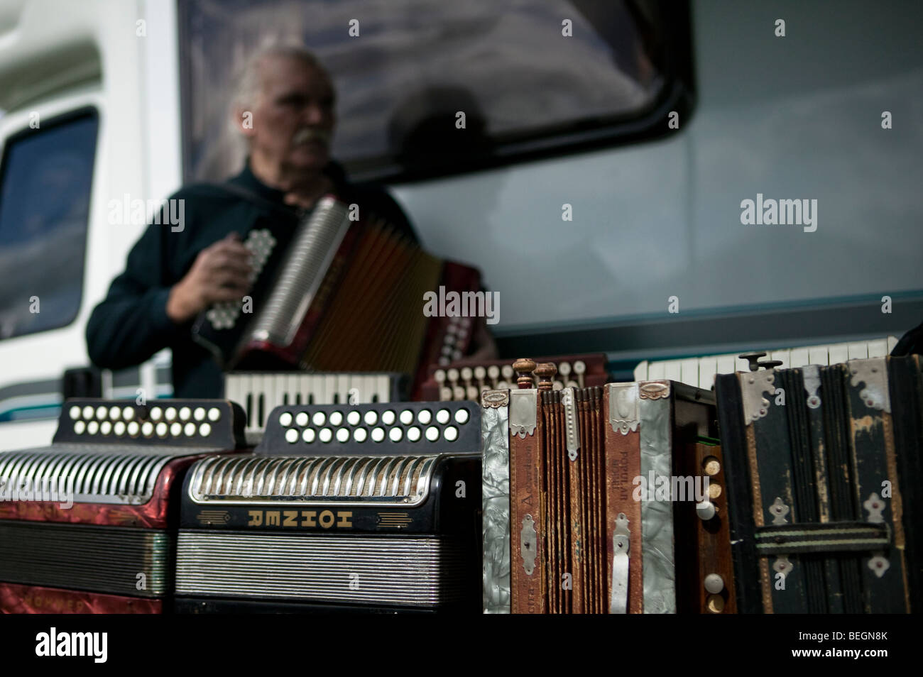 An old man plays on of his many accordions for sale at a steam and vintage fair. Stock Photo