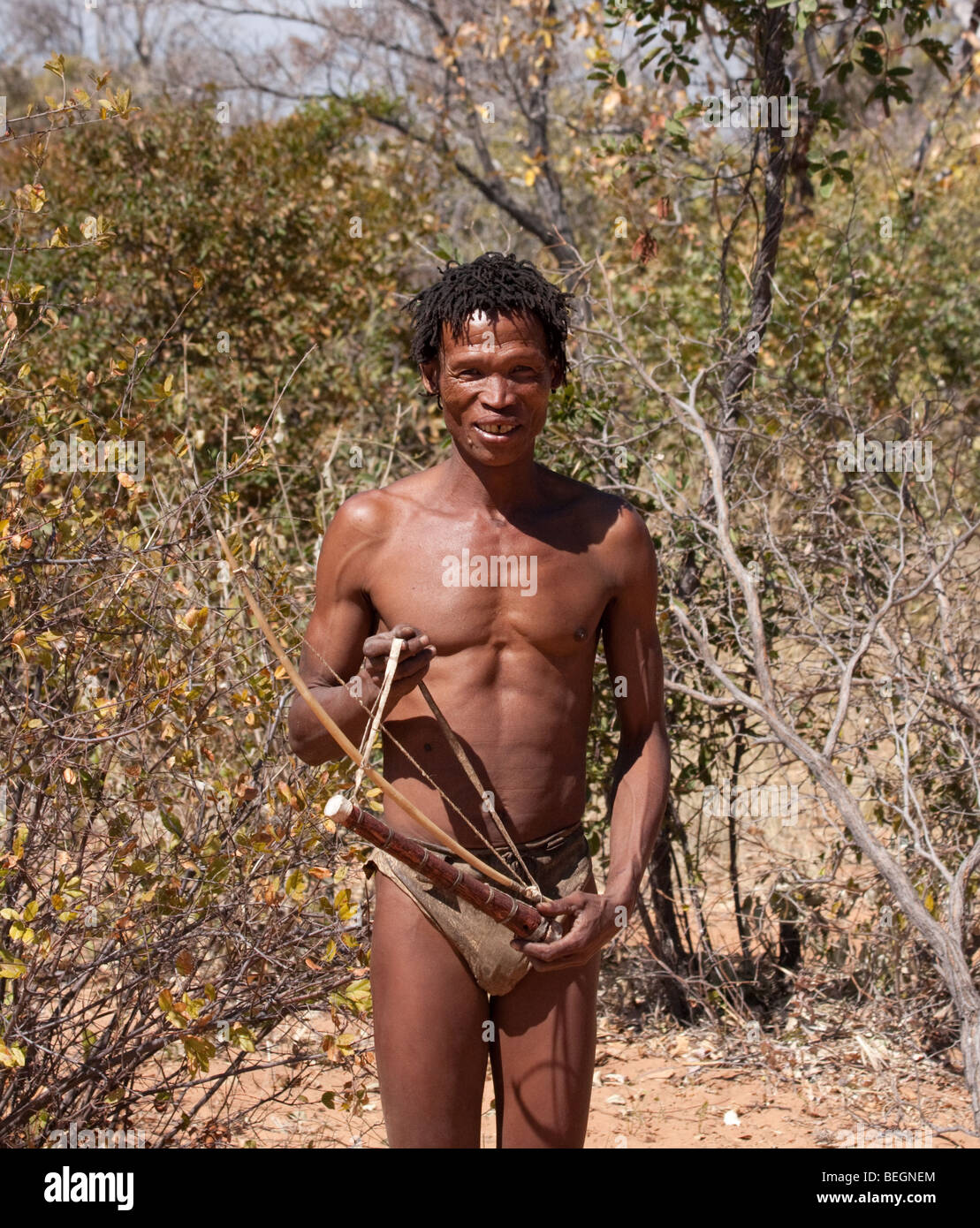 San Village. A San hunter poses with a bow and quiver full of arrows that he has made. Stock Photo