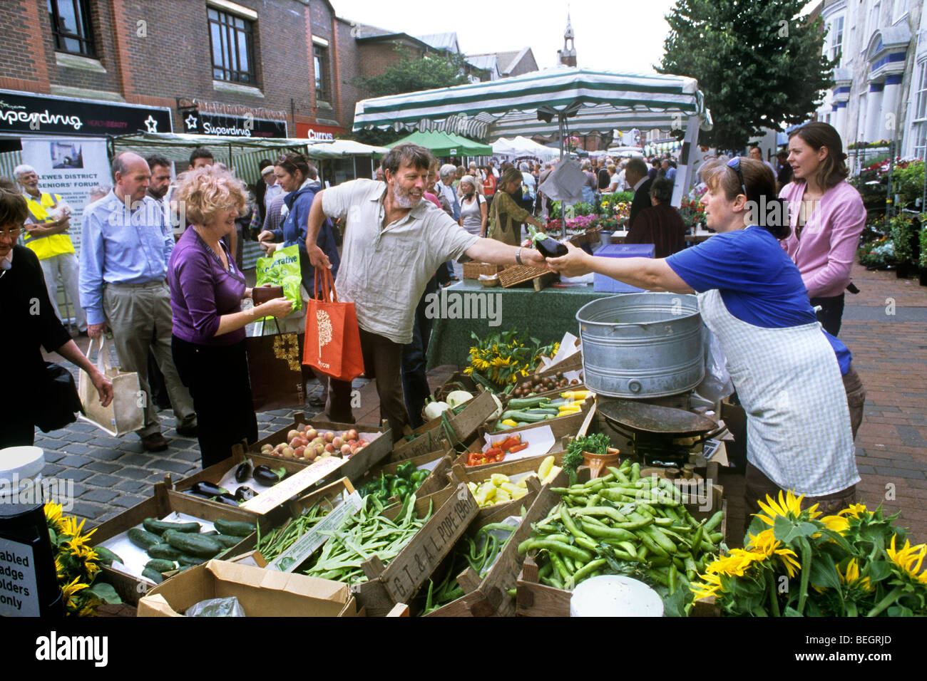 Buying an aubergine at a vegetable stall at Lewes farmers' market, Lewes, East Sussex. Stock Photo