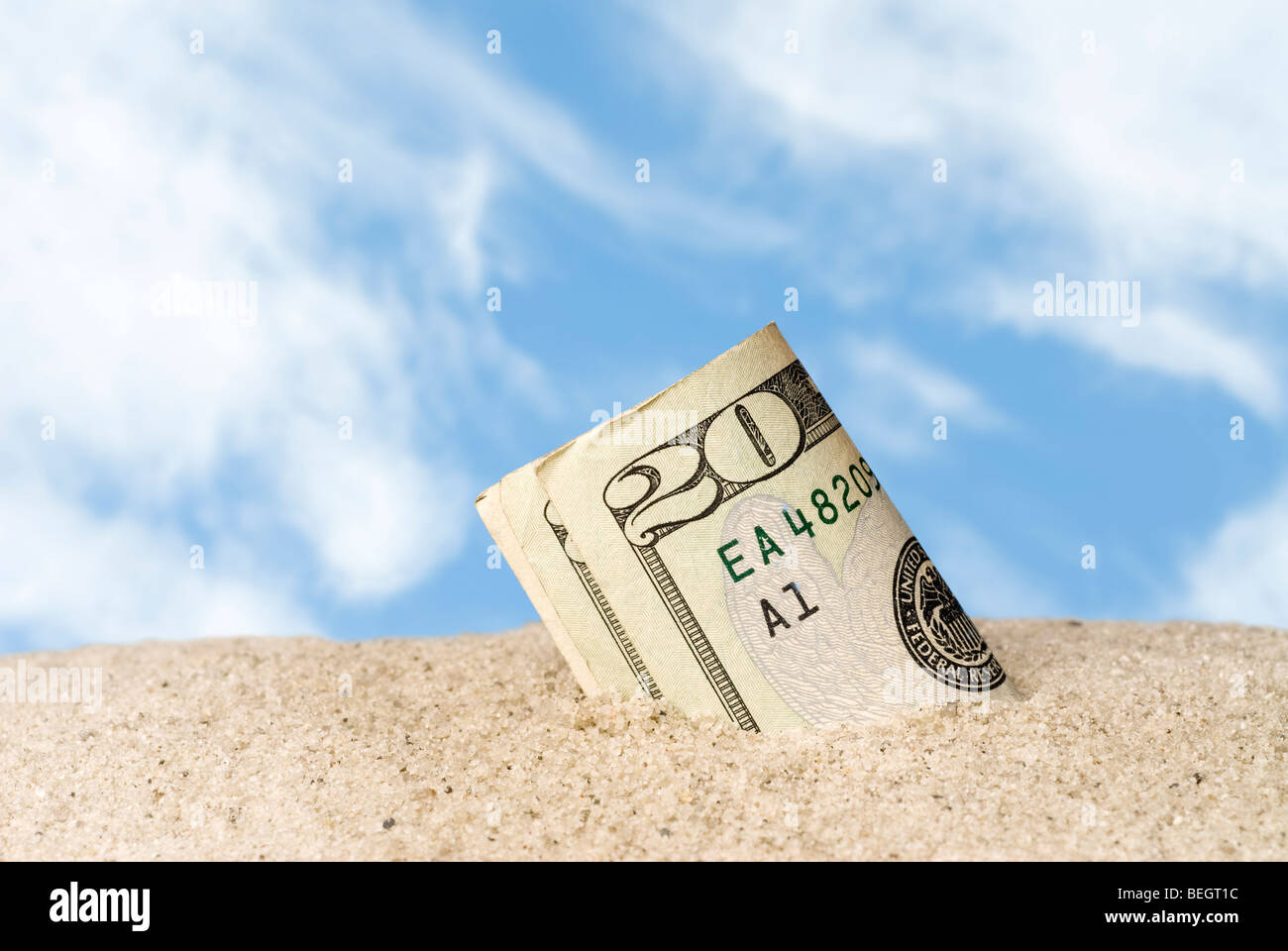 A wad of cash lost and found in the sand at the beach. Stock Photo