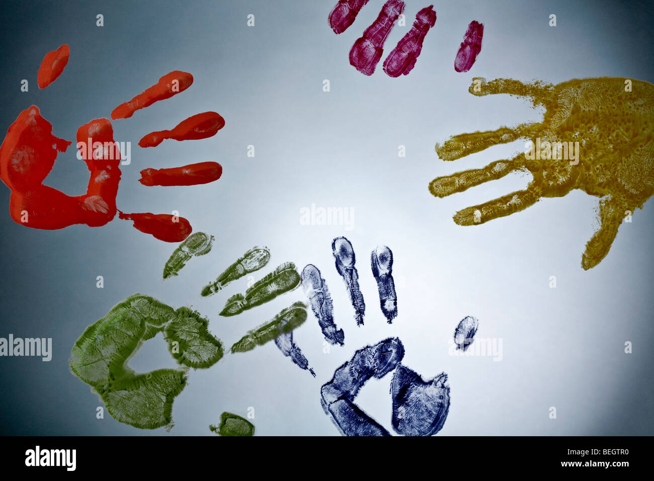 A photograph of hand palm prints of different colours on glass. Stock Photo