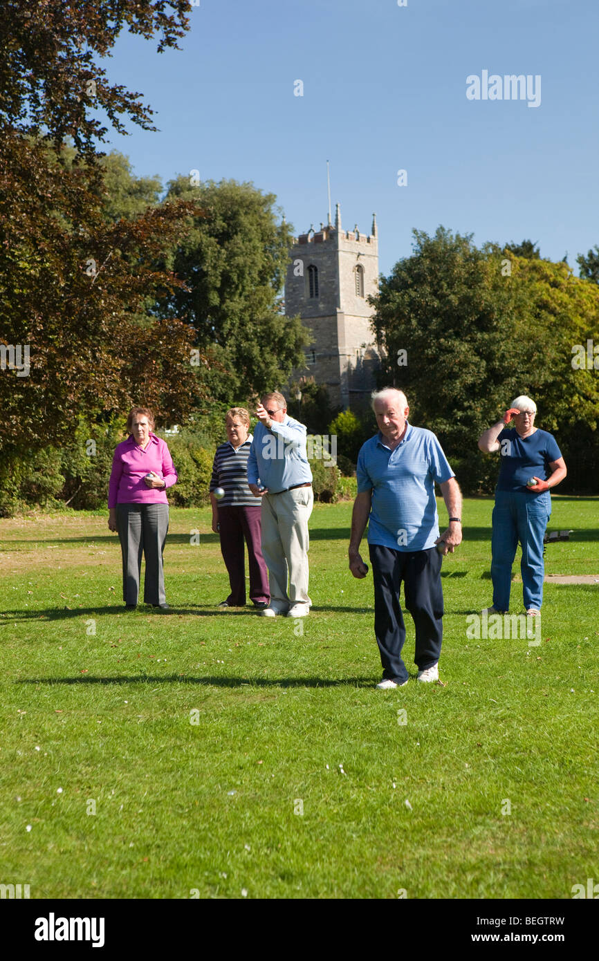 England, Cambridgeshire, Huntingdon, Hartford, pensioners playing boules on riverside green below church tower Stock Photo