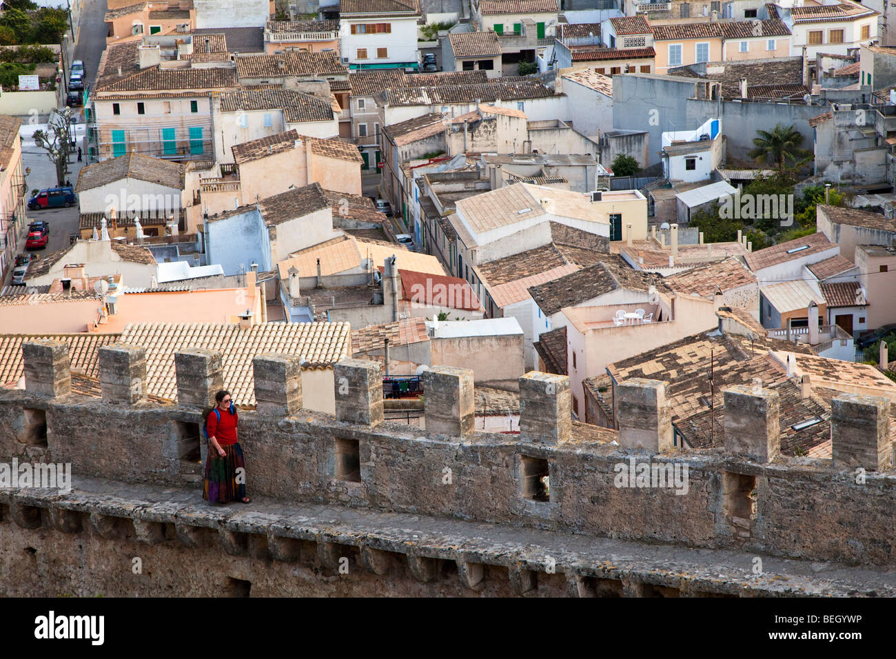 Woman visitor walking on battlement wall with town behind Castell des Capdepera Mallorca Spain Stock Photo