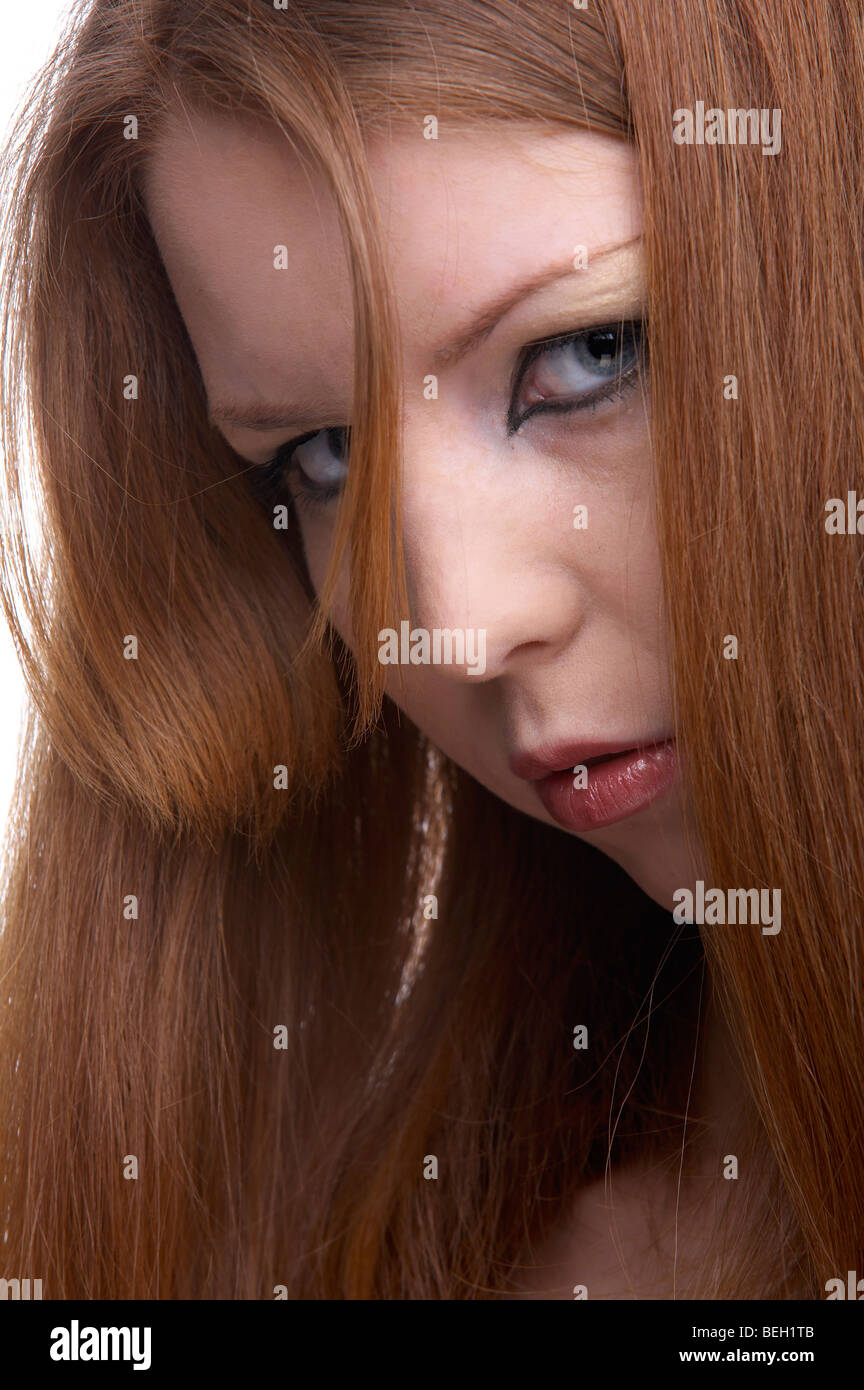 close-up portrait of beautiful redhead pale skinned model turns and looks frowningly Stock Photo