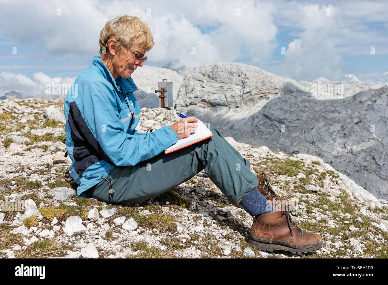 Female walker signing the visitors book on Mala Zelnarica in the Julian Alps, Slovenia. Stock Photo
