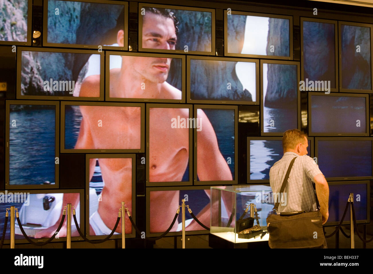 Fragrance male model advertising images on screen matrix at World of Duty Free at Heathrow's Terminal 5. Stock Photo