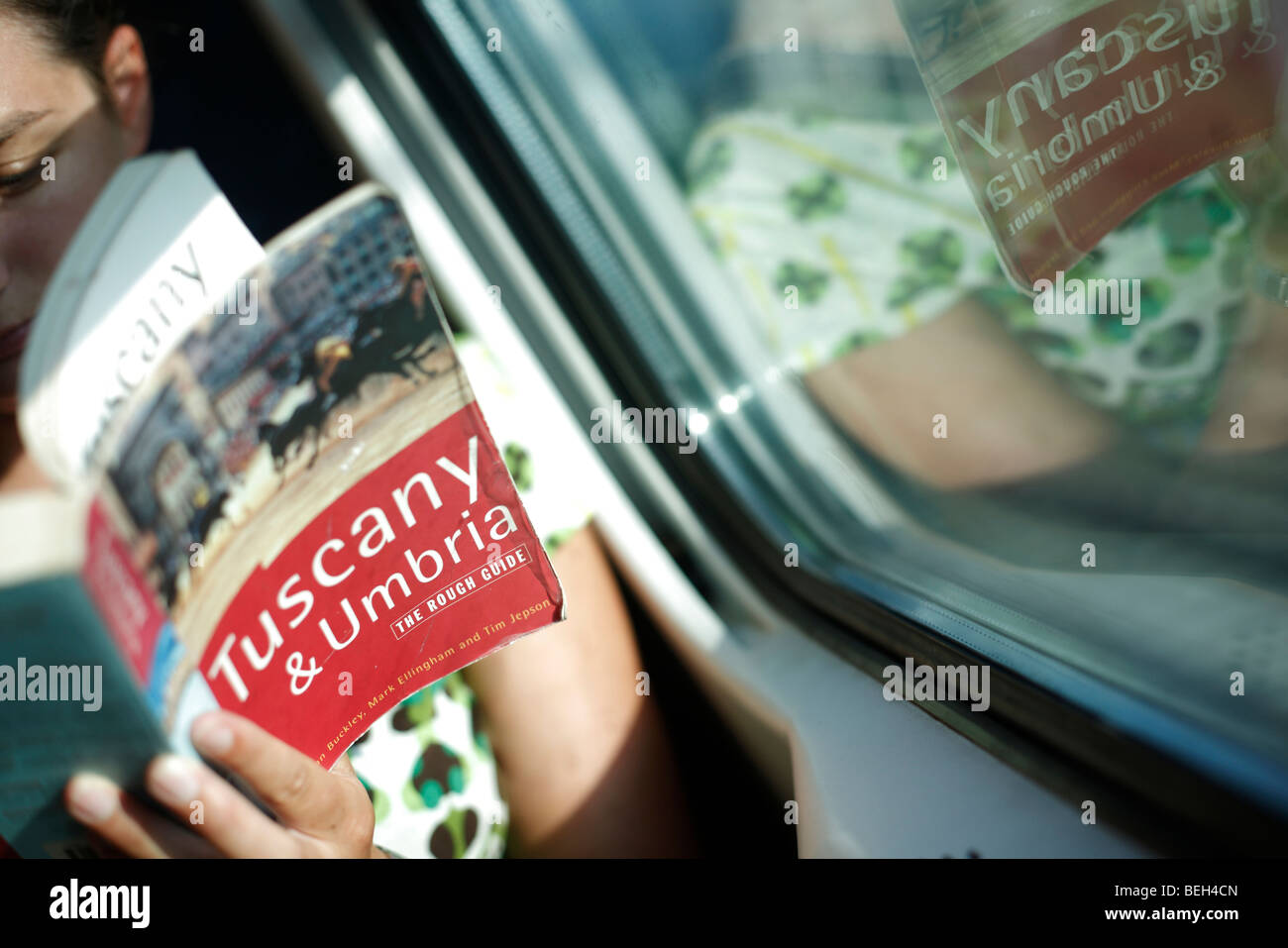 A woman reads a copy of the Rough Guide to Tuscany and Umbria on a train in Italy Stock Photo
