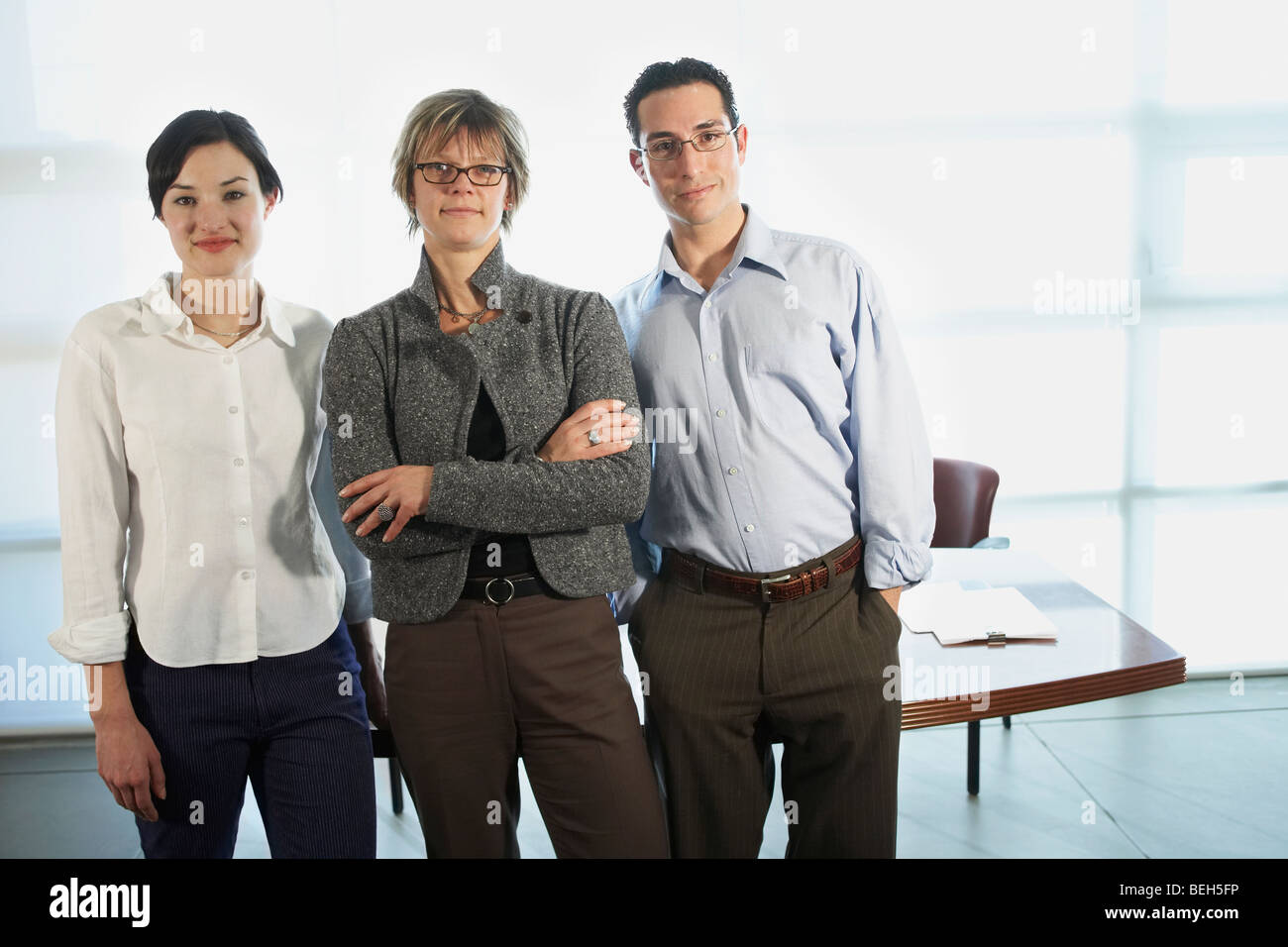 Portrait of two businesswomen and a businessman standing in an office ...