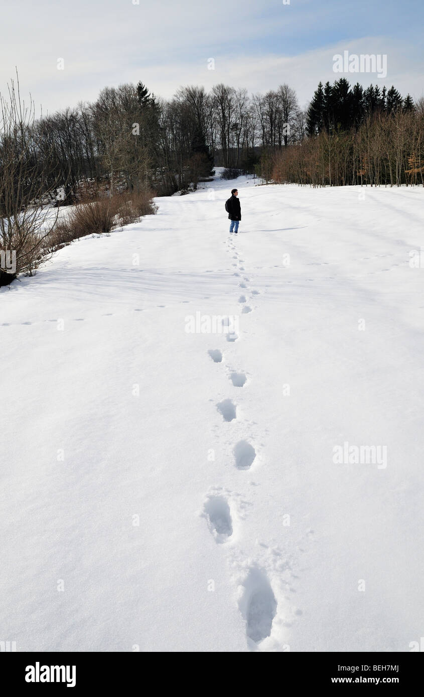 Footsteps in the snow leading to a person Stock Photo