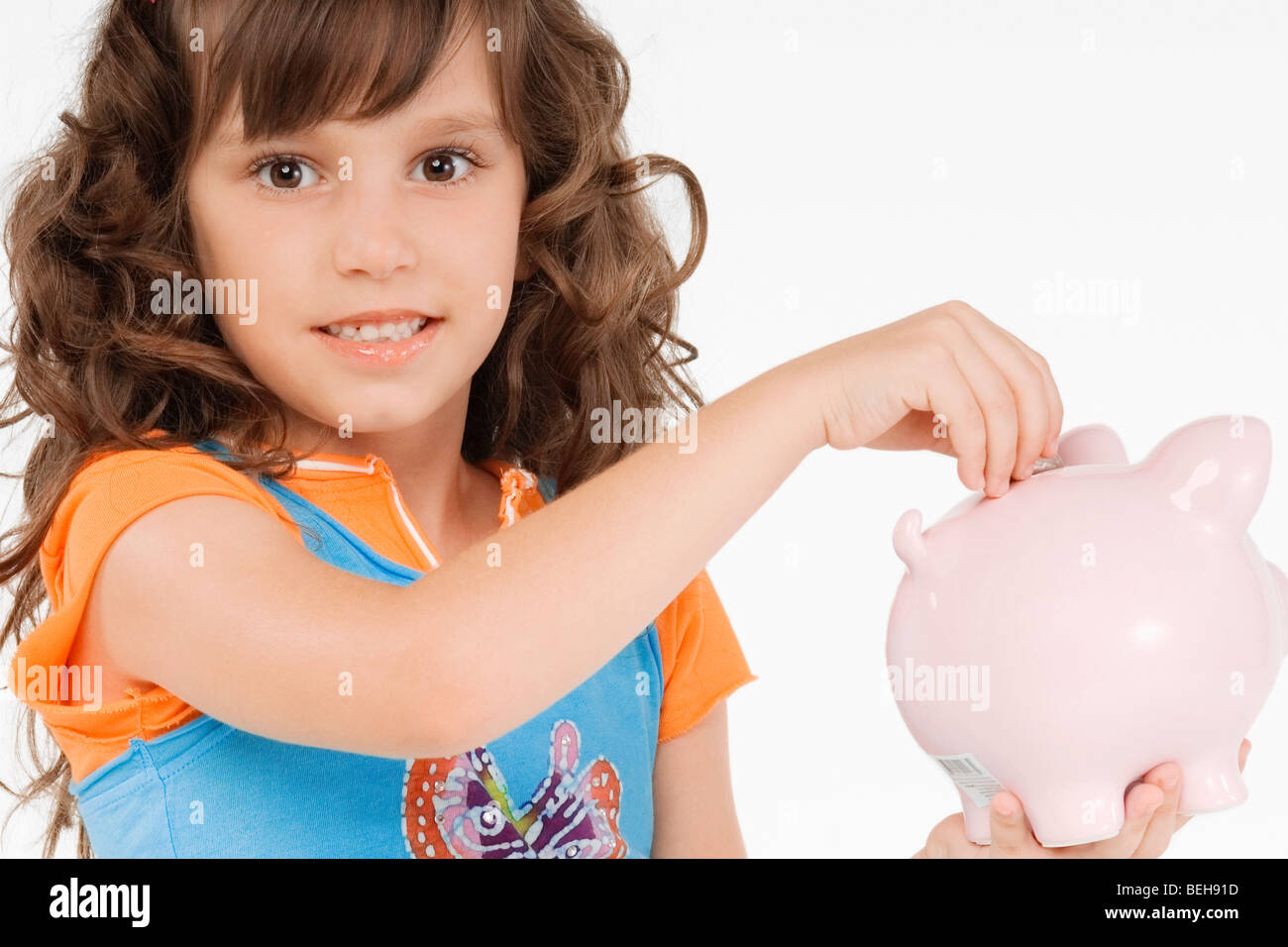 Portrait of a girl putting a coin into a piggy bank Stock Photo - Alamy