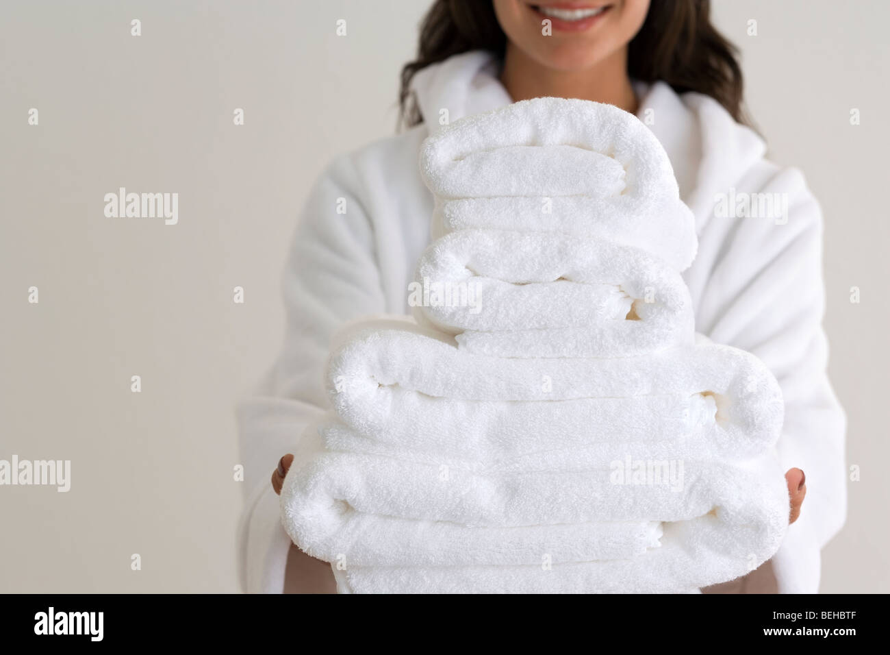 Mid section view of a young woman holding a stack of towels and smiling ...