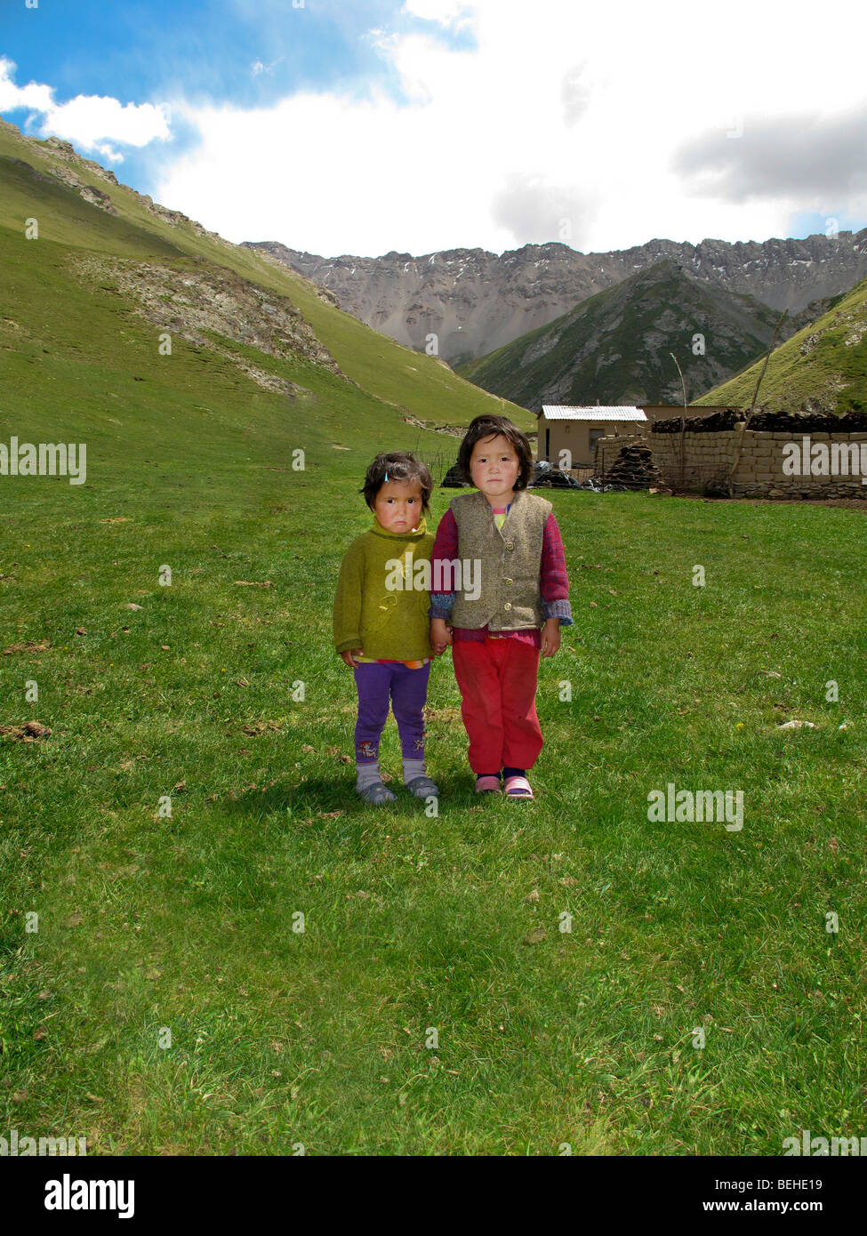 two small girls standing outside their summer dwelling near Tash Rabat, in the Tian Shan mountains, eastern Kyrgyzstan. Stock Photo