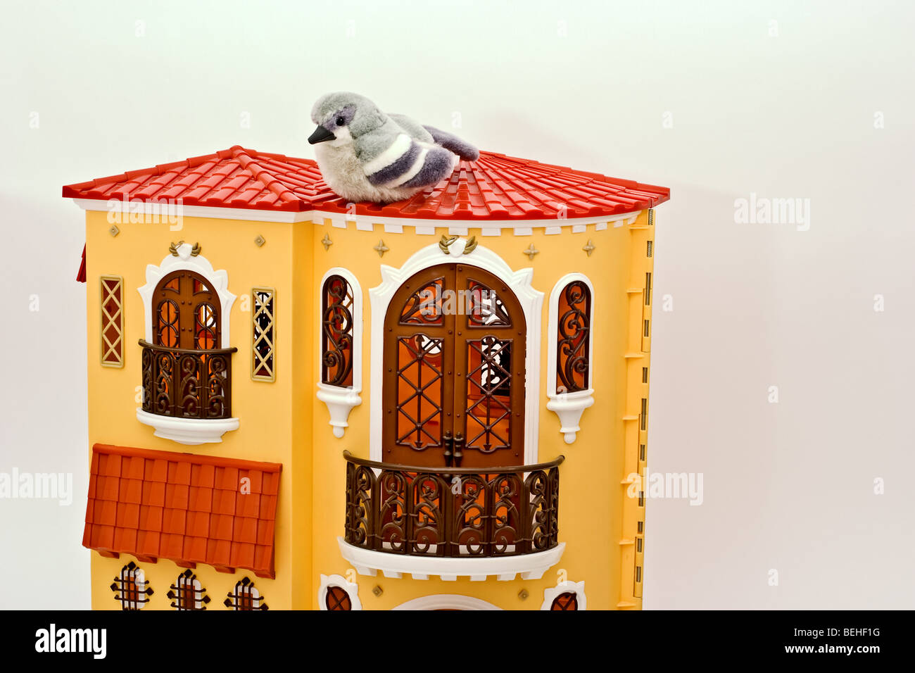 Bird toy sitting on top of an elaborate European style doll house Stock Photo