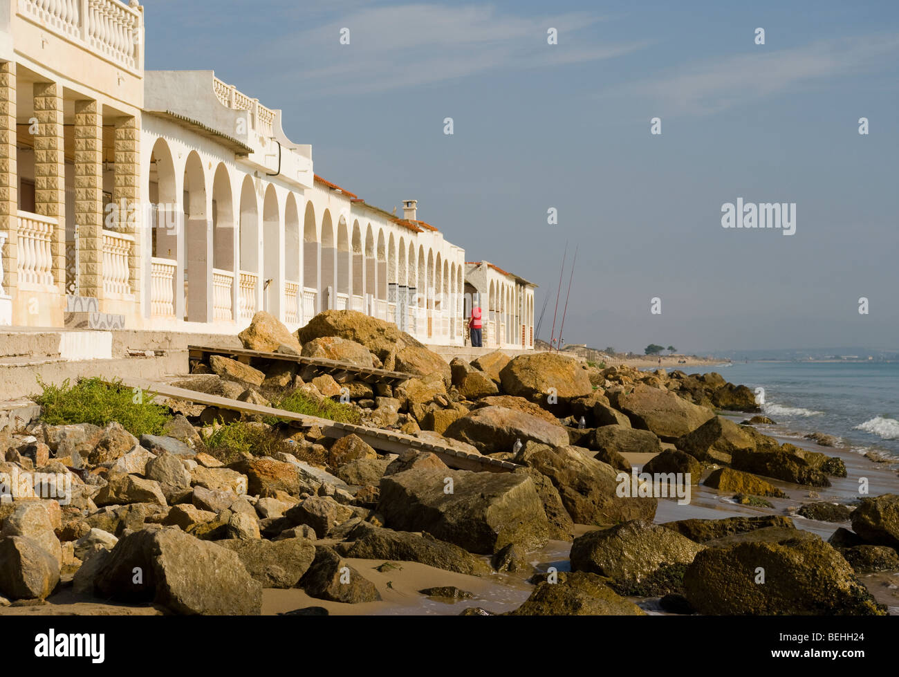 Arched Frontage Of Beachfront Holiday Villas Playa Del Pinet La Marina Spain With A Rocky Foreshore Stock Photo