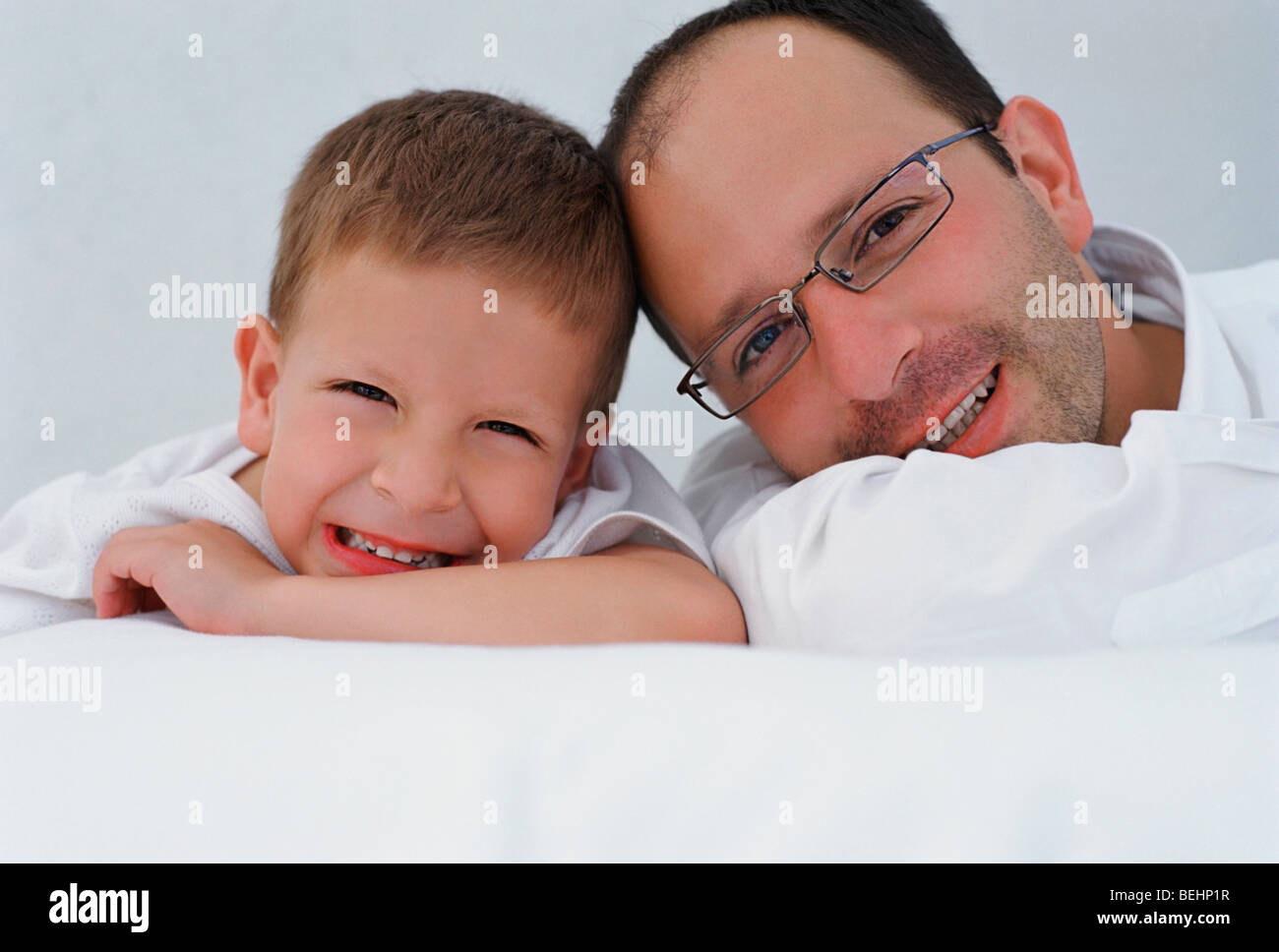 Portrait of a mid adult man with his son lying on the bed and smiling ...