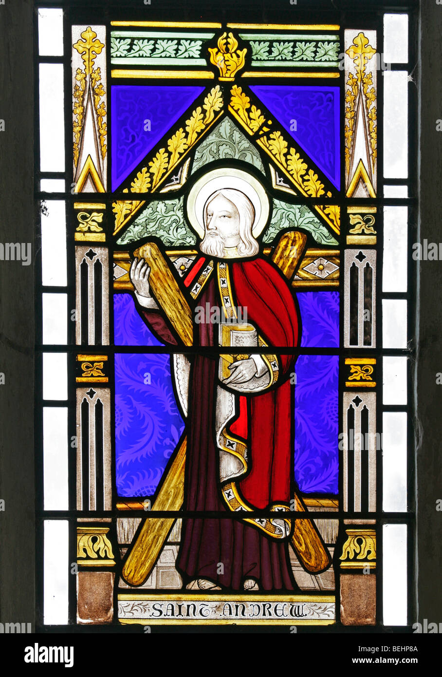 A stained glass window depicting St Andrew the Apostle holding a wooden saltire, All Saints Church, Wighton, Norfolk by Joseph Grant of Costessey Stock Photo