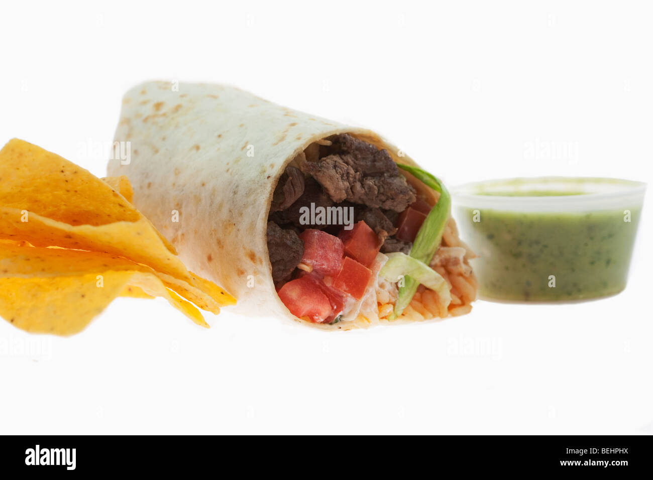 Close-up of a beef burrito with tortilla chips and salsa verde Stock Photo