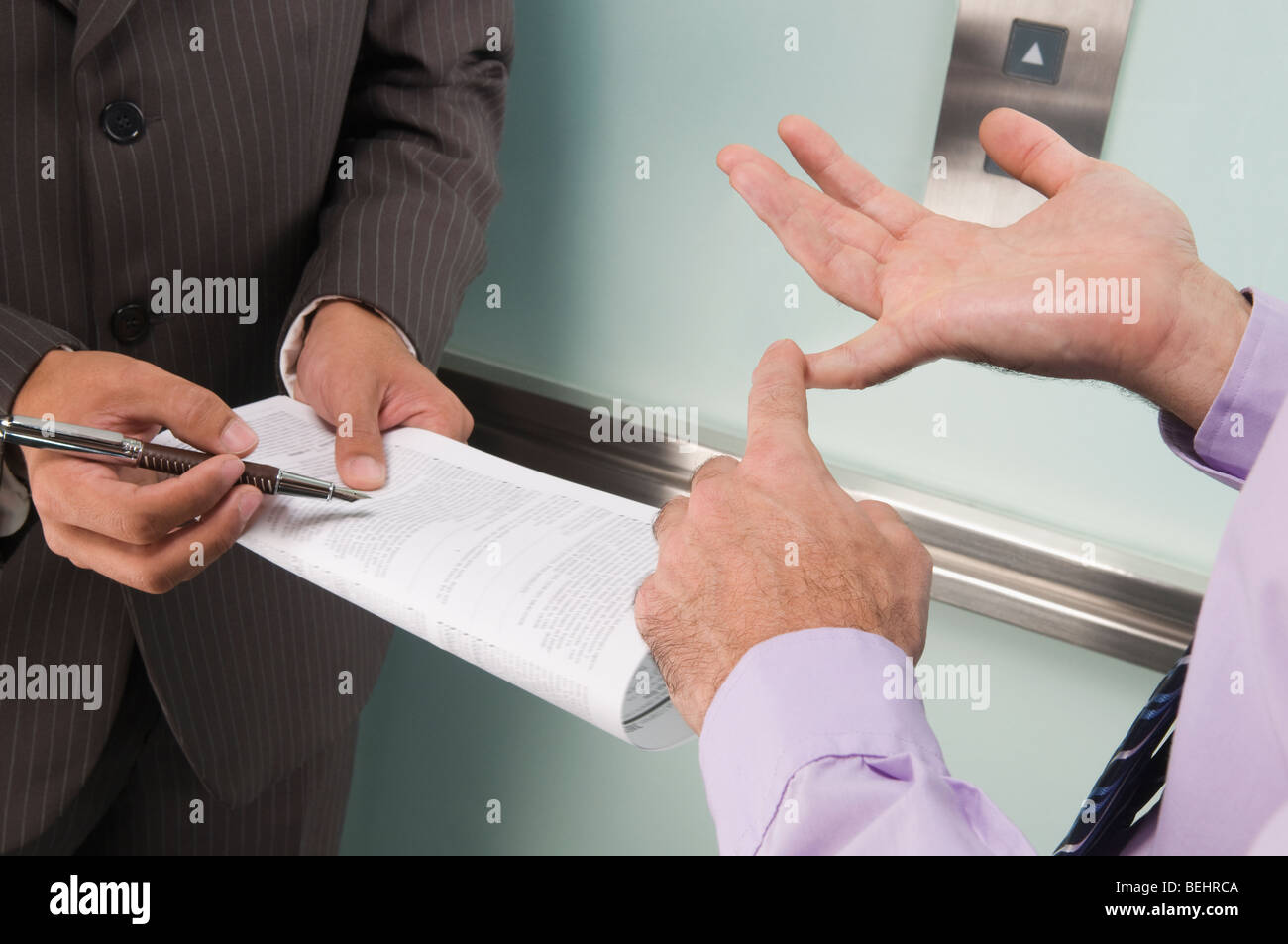 Businessmen discussing in an elevator Stock Photo